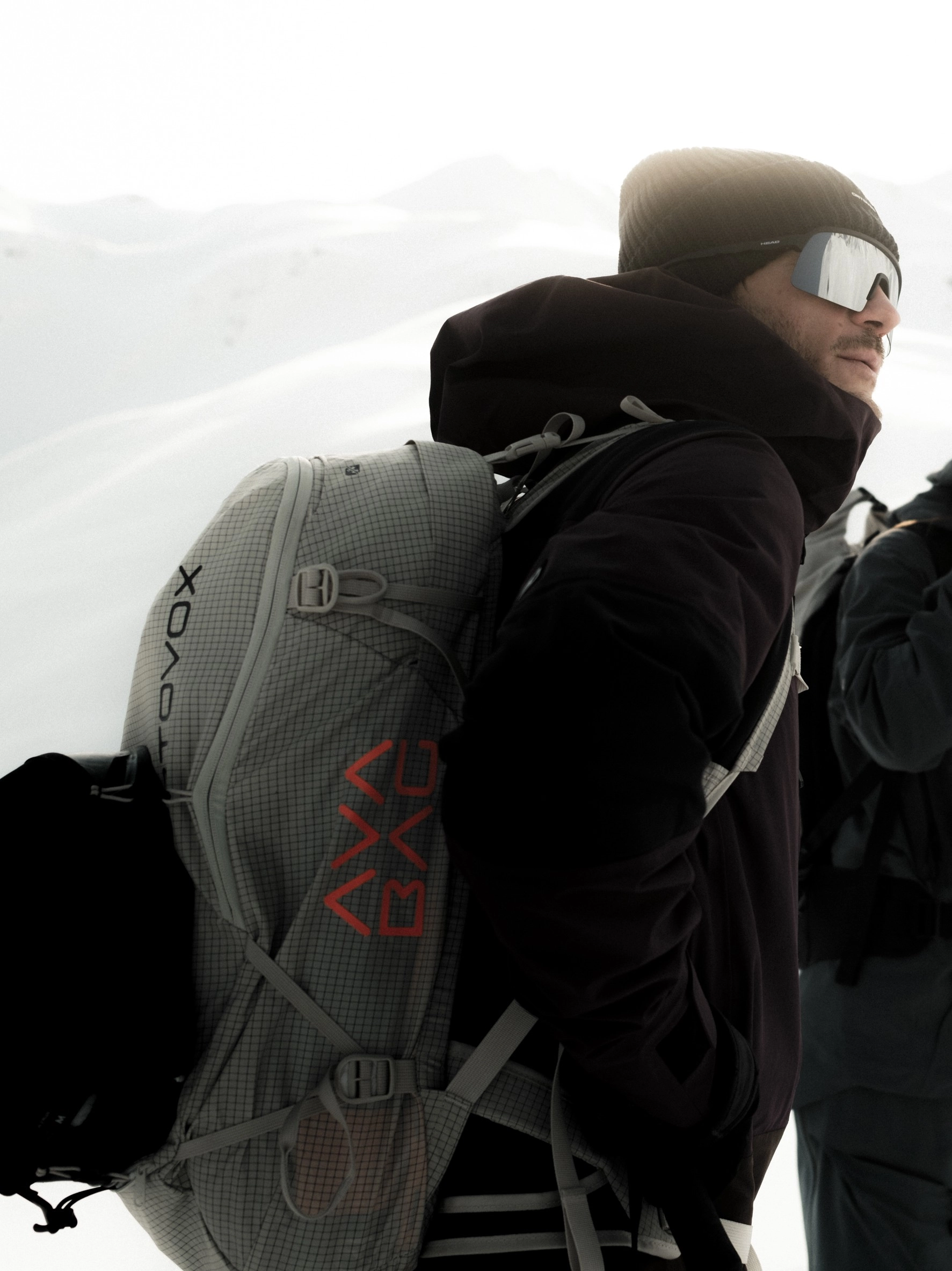 DSF9298_FREERIDE_WS2526_Georgien-Mestia_MaxDraeger_MedRes_(1) ski backpack, gray grid pattern, technical fabric, red logo, adjustable straps